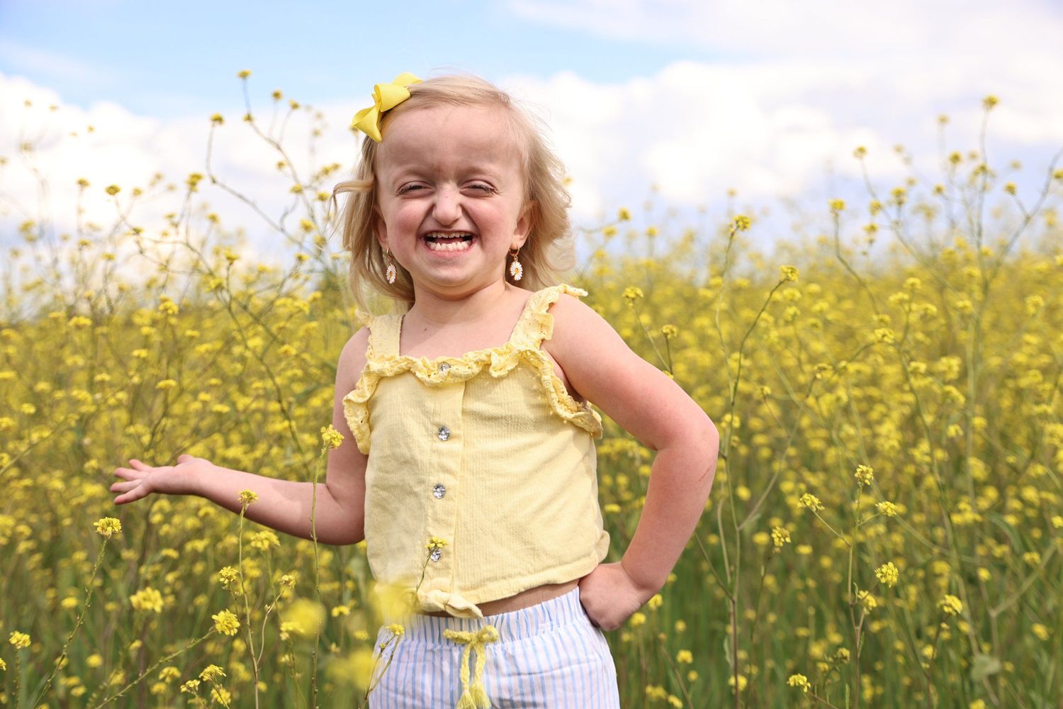 Joyful child wearing yellow top playing in a vibrant field of yellow wildflowers on a sunny day in Abilene, Texas.