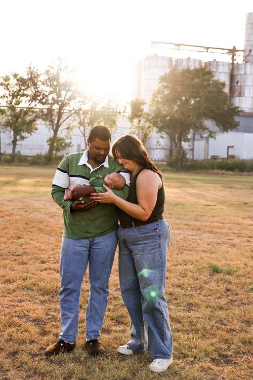 Couple admiring their newborn baby in a sunlit field at golden hour in Abilene, Texas.