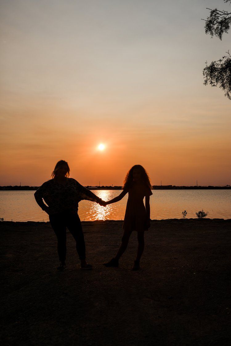 Silhouetted couple holds hands against an orange sunset over water in Abilene, Texas.