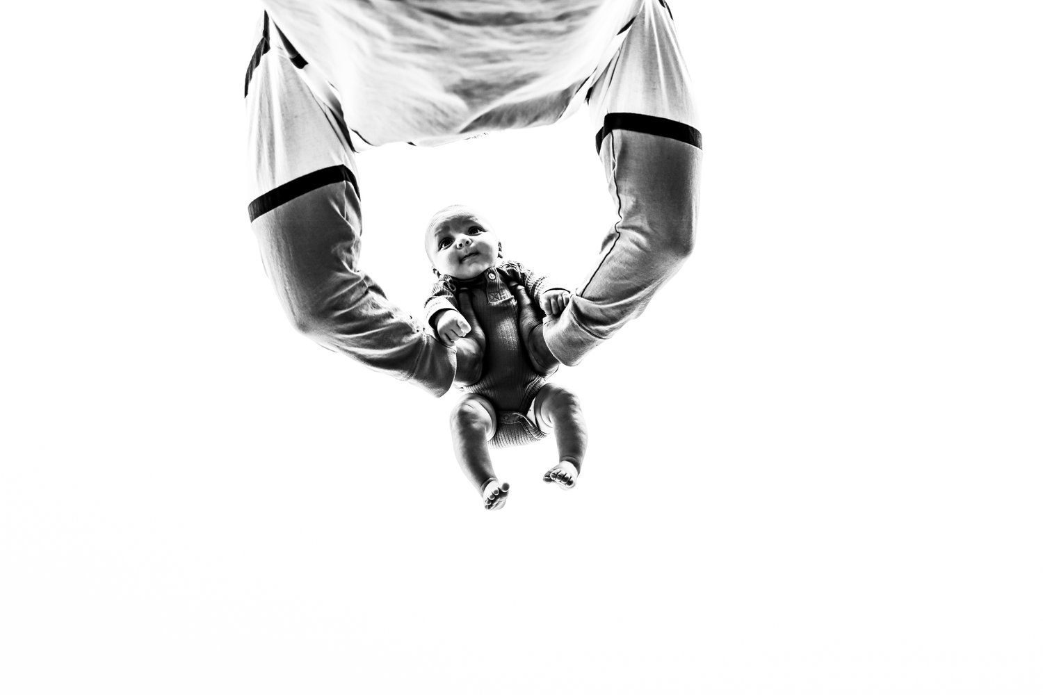 High contrast black and white image of a baby being lifted up against a white background in Abilene, Texas.