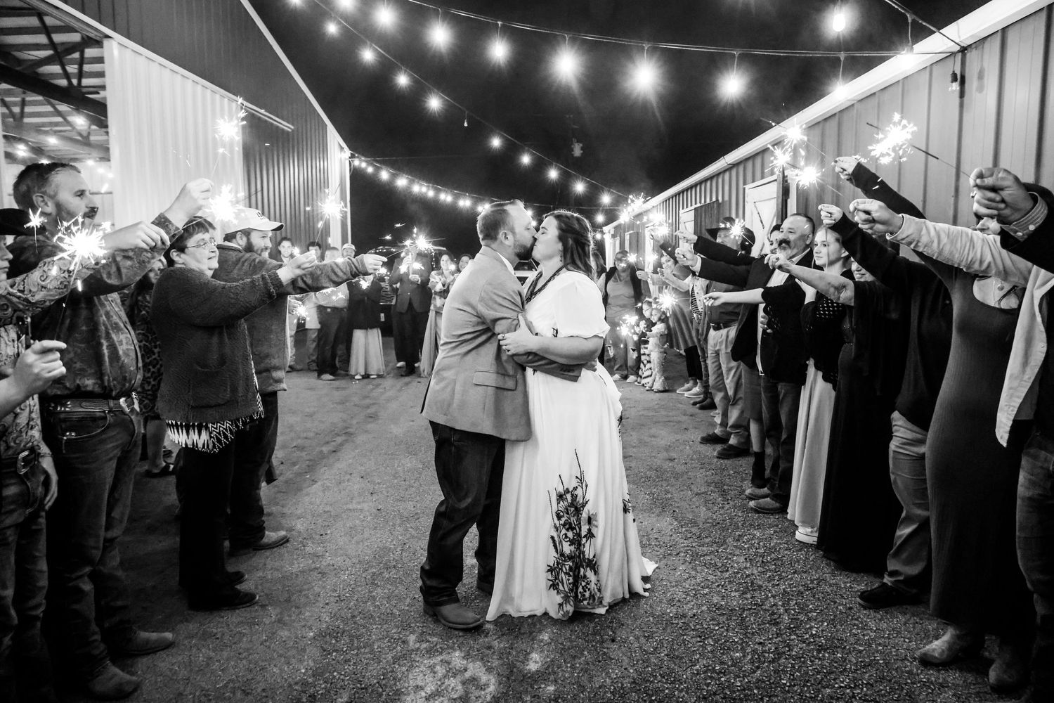 Black and white wedding exit with couple walking through sparkler tunnel surrounded by guests at night in Abilene, Texas.