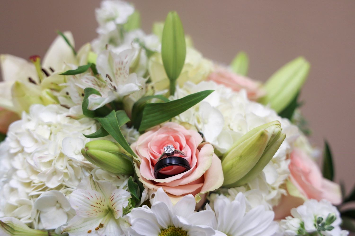 Close-up of elegant wedding bouquet with pink roses and white hydrangeas with green foliage.
