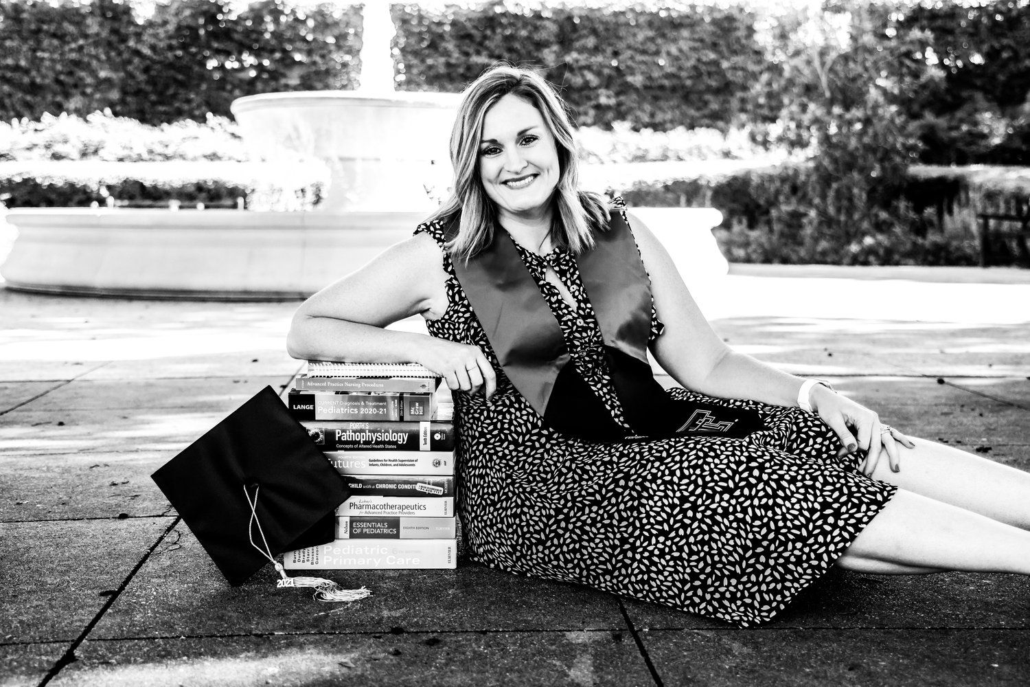 Casual black and white portrait of woman sitting outdoors near fountain in Abilene, Texas.