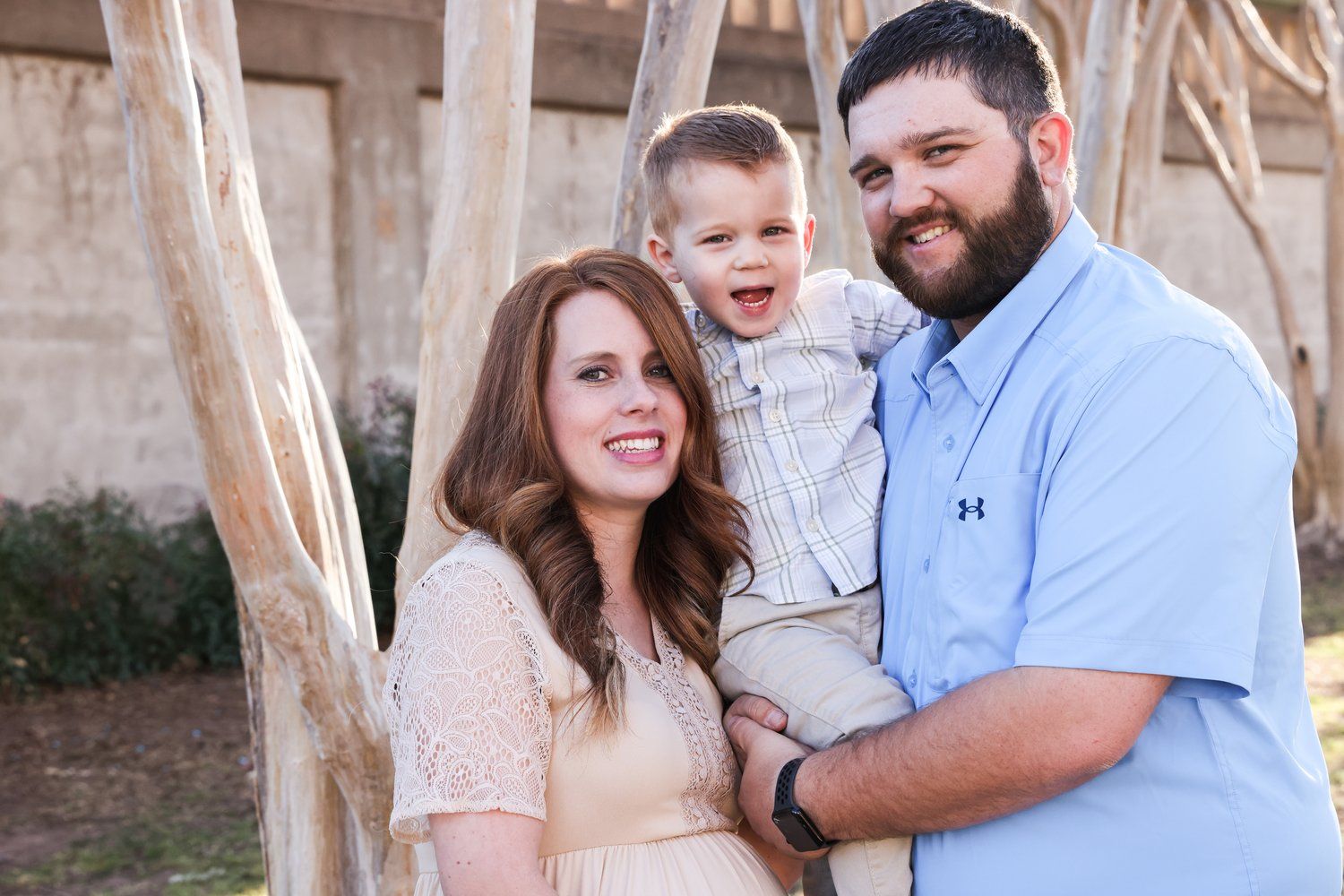 Family portrait outdoors with soft natural lighting against a rustic building wall in Abilene, Texas.