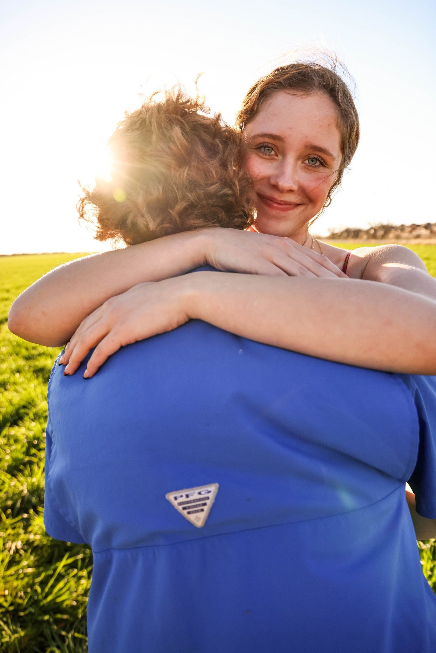 Two people embracing in a sunlit field during golden hour in Abilene, Texas.