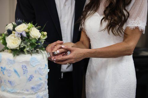 Couple cutting an elegant blue and white wedding cake together.