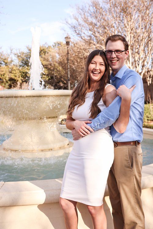 Happy couple embracing by a fountain on a sunny day in Abilene, Texas.