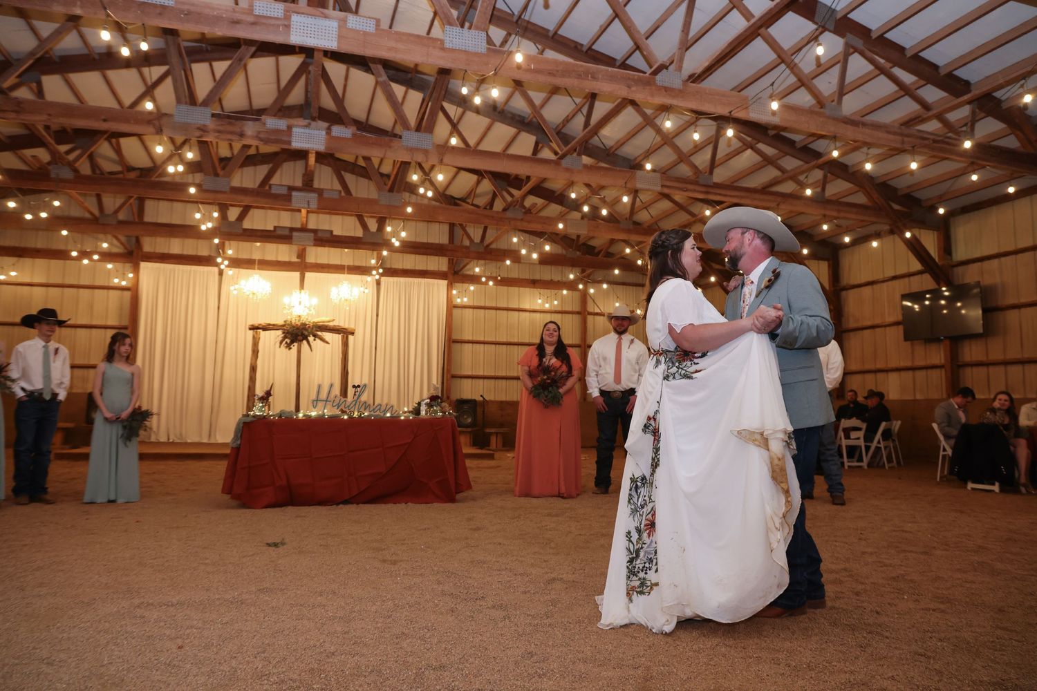 Dancing couple in wedding dress and suit under string lights in a rustic barn venue in Abilene, Texas.