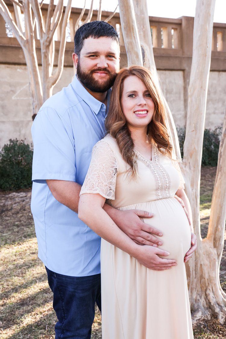 Expecting couple embraces outdoors near white birch trees during maternity photoshoot in Abilene, Texas.