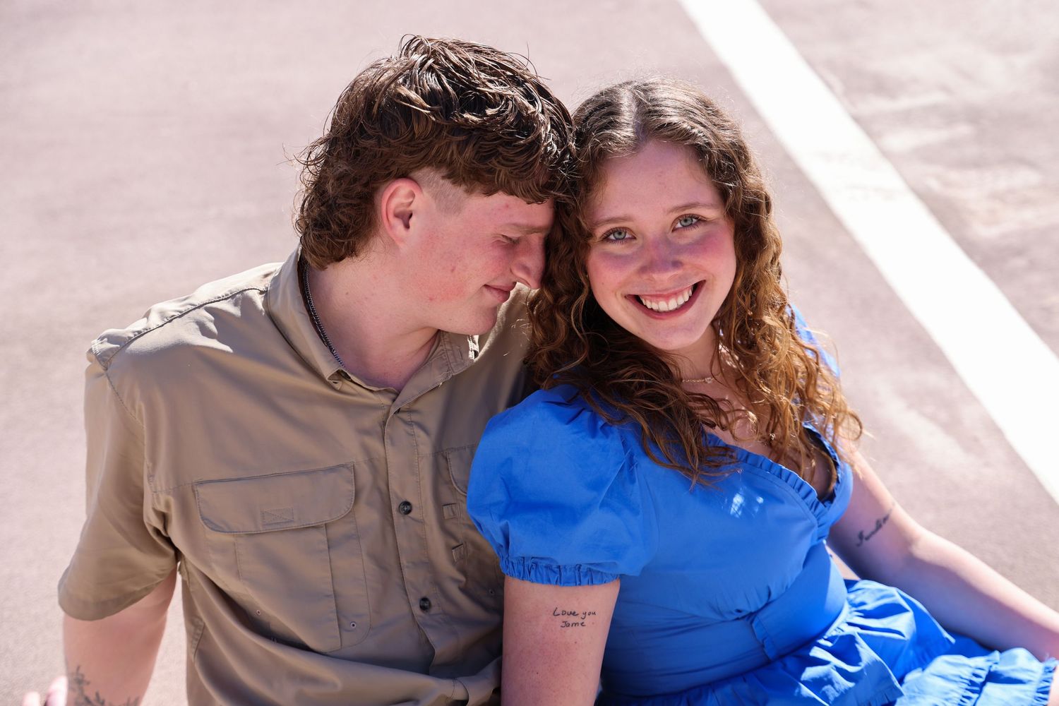 Happy couple in casual wear sitting together and smiling in sunlit setting in Abilene, Texas.