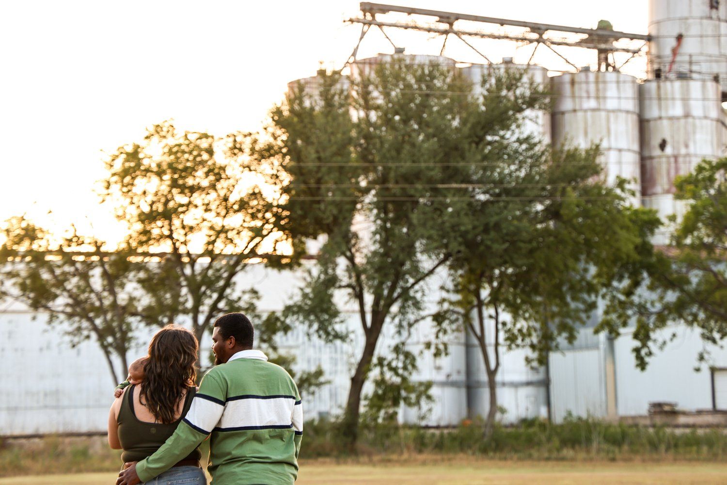 Couple embracing while watching sunset near industrial buildings in Abilene, Texas.