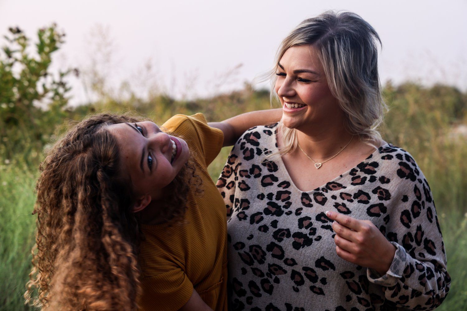 Two friends share laughter during an outdoor portrait session in Abilene, Texas.
