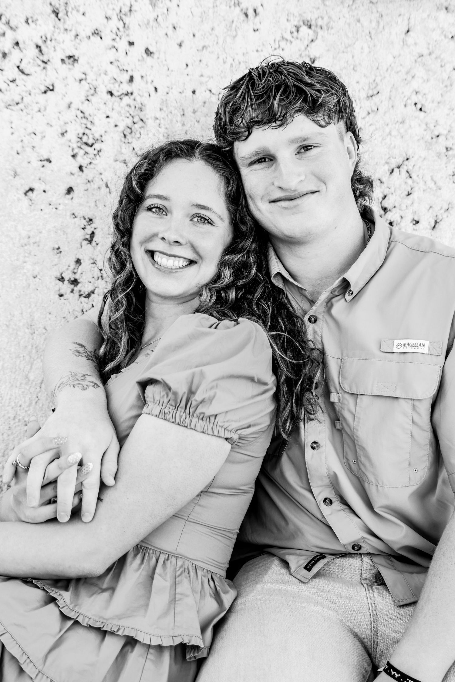 Black and white portrait of couple in matching outfits smiling at camera in Abilene, Texas..