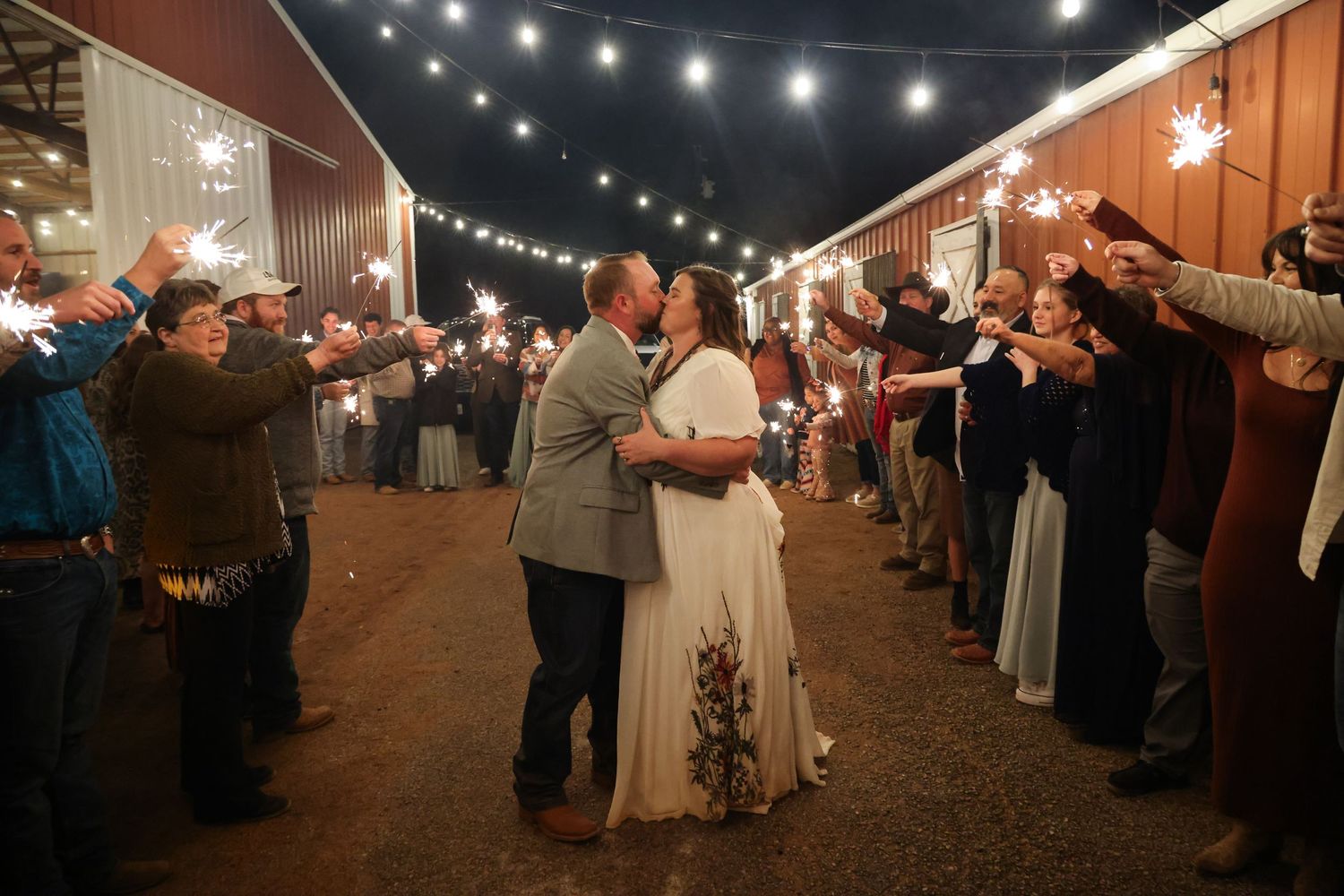 Couple celebrates their wedding exit in Abilene Texas with guests holding sparklers during outdoor evening wedding exit.