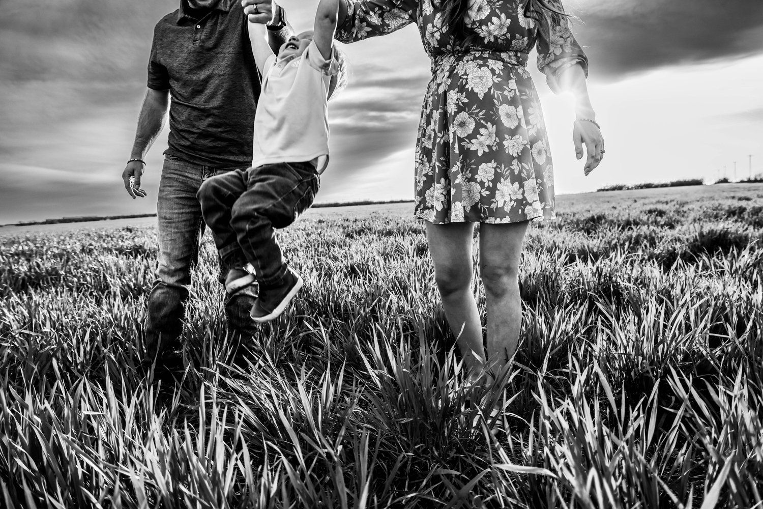 Black and white image of family legs walking through a field together in Abilene, Texas.