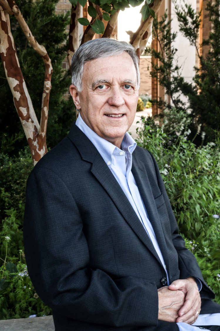 Professional headshot of gentleman in business attire against garden backdrop with birch trees in Abilene, Texas.