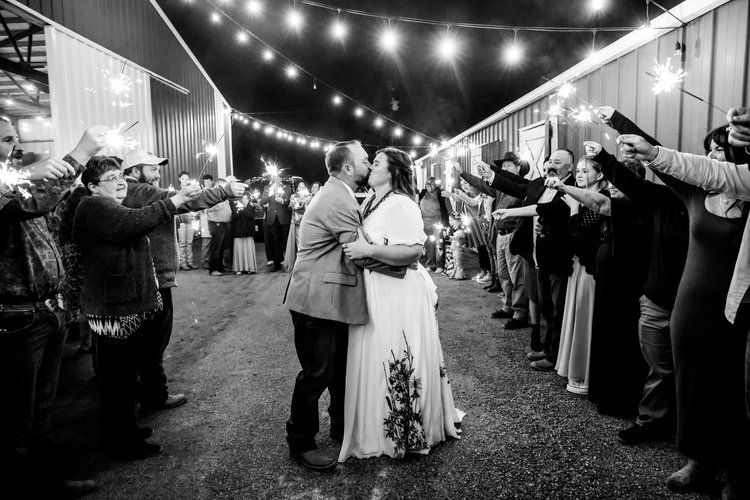 A romantic wedding celebration under string lights with guests forming a tunnel for the couple in Abilene, Texas.