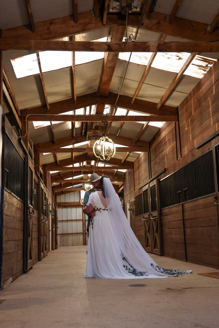 Dramatic wedding portrait in a sunlit horse stable hallway in Abilene, Texas.