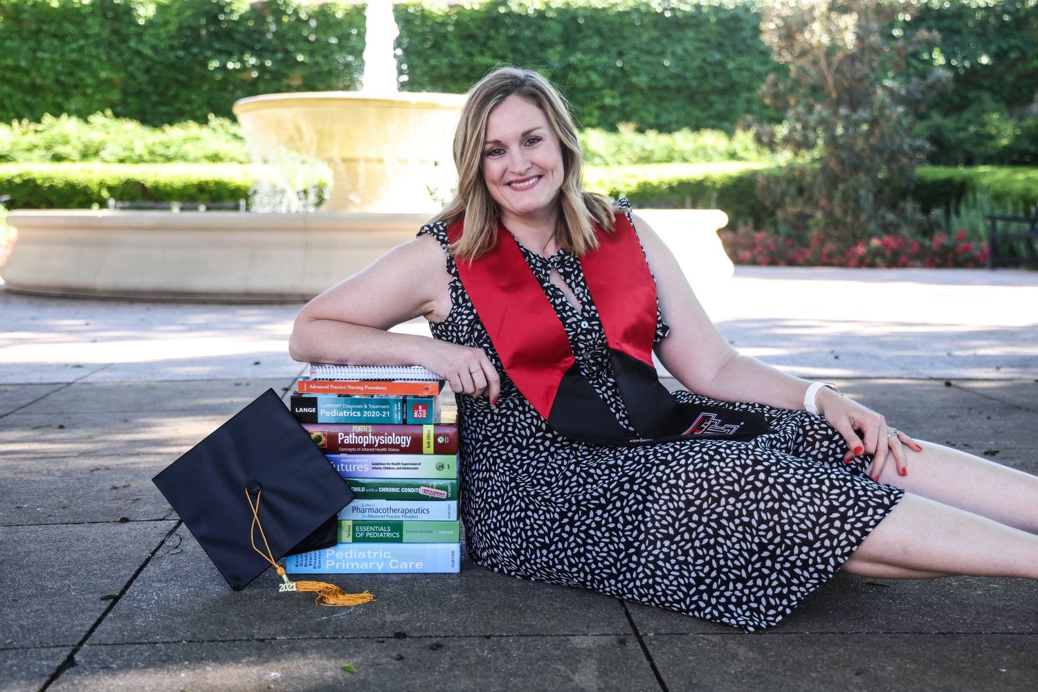 Person sitting by fountain with stack of books and polka dot dress in Abilene, Texas.