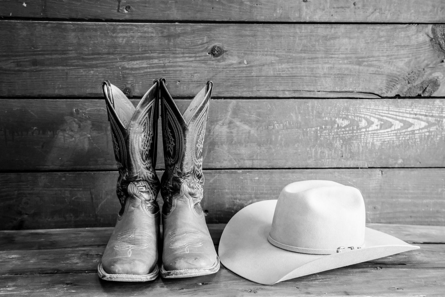 Weathered cowboy boots and white cowboy hat arranged on rustic wooden background in Abilene Texas.