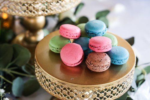 Colorful French macarons displayed on a gold decorative plate with eucalyptus leaves in Abilene, Texas.