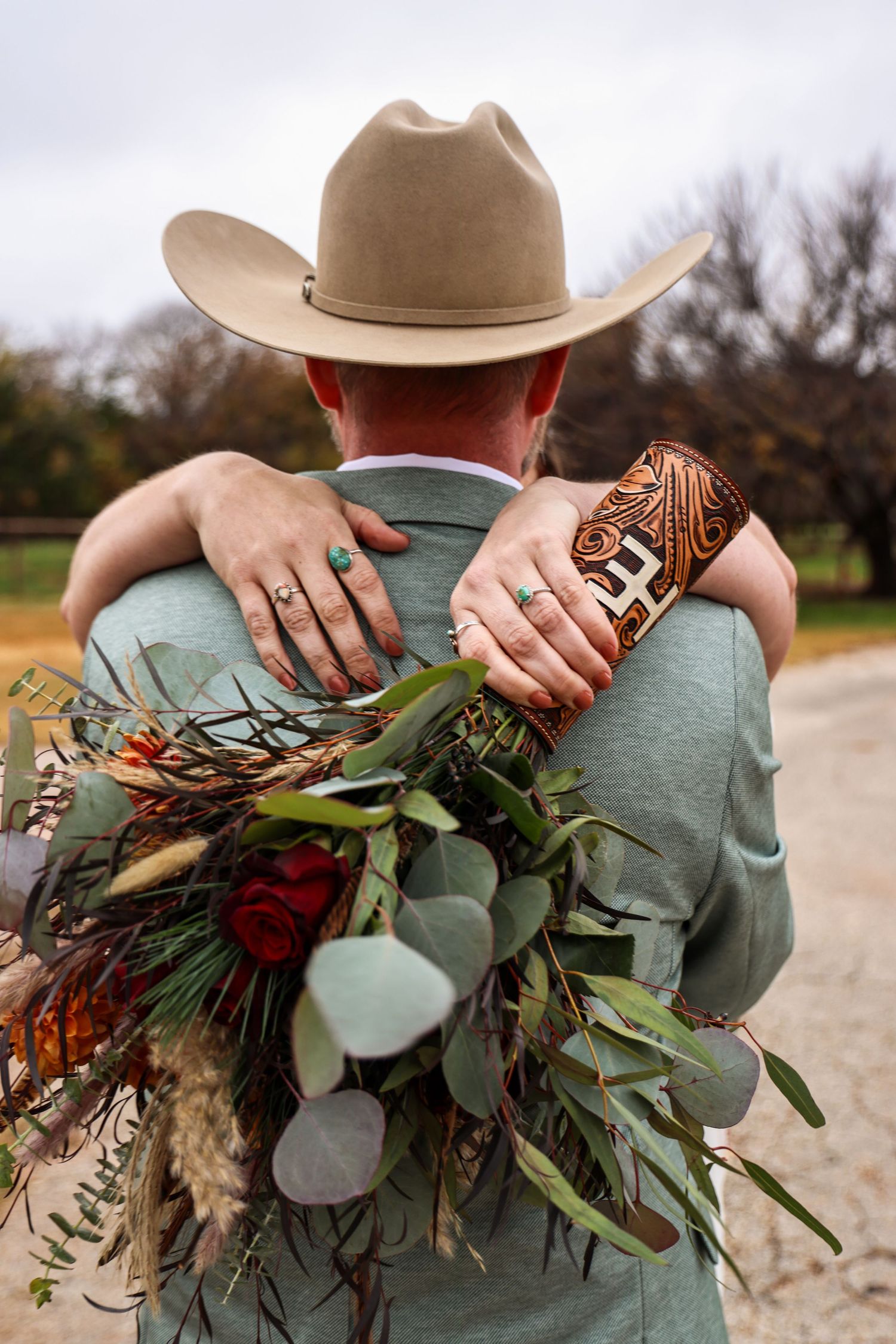 Wedding bouquet and tooled leather wallet against a cowboy wearing green and a tan hat in Abilene, Texas.