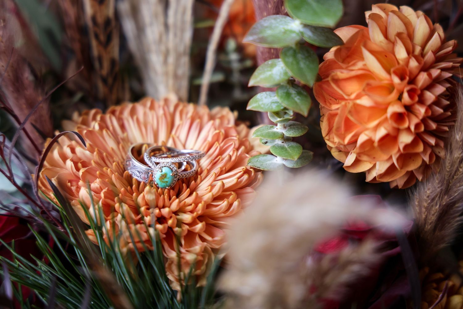 Wedding rings nestled in western rustic coral-colored flowers with greenery in Abilene, Texas.
