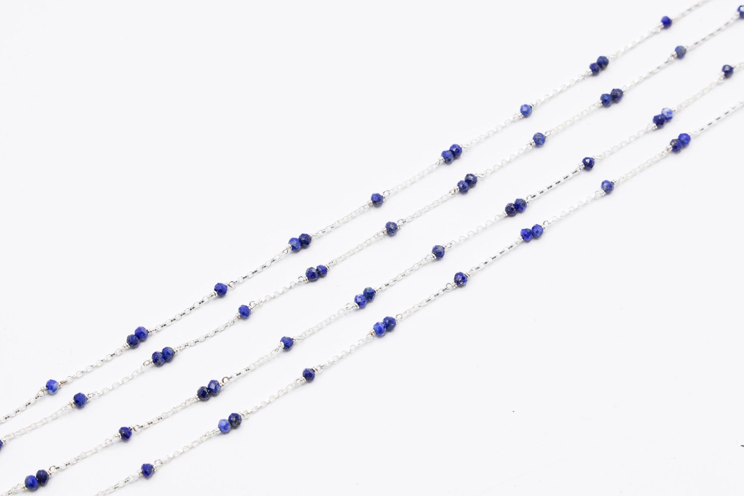 Dainty silver chain necklace with evenly spaced blue sapphire beads in a linear pattern.