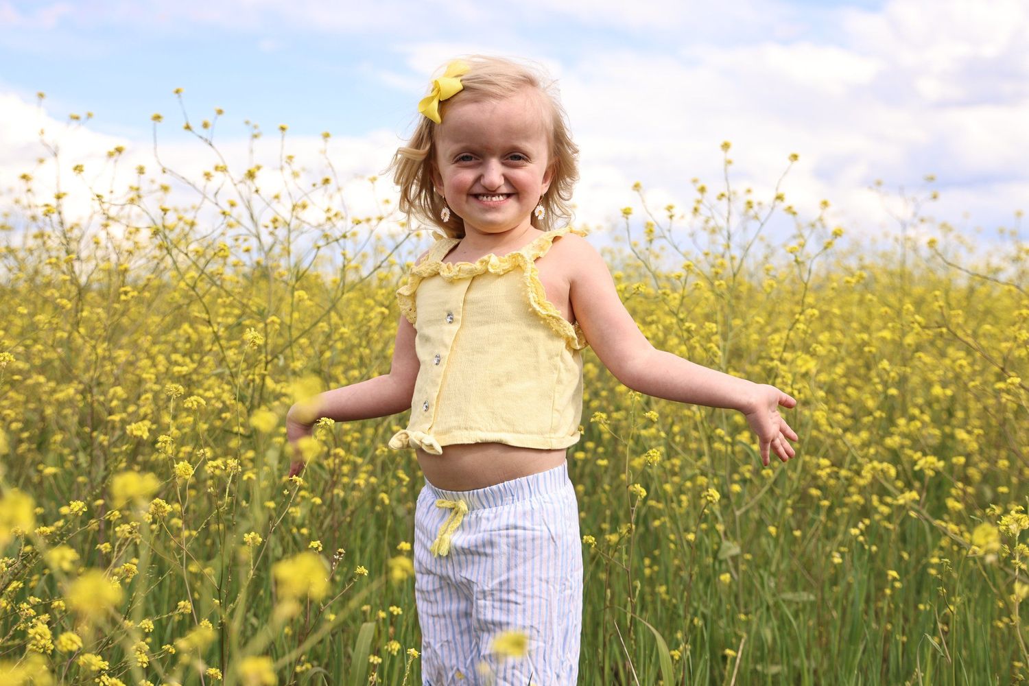 A joyful child plays in a blooming yellow canola flower field on a sunny day in Abilene, Texas.