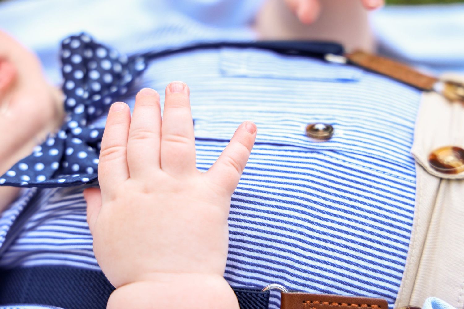 Small hands touch a striped fabric with polka dot bow tie and buttons in Abilene, Texas.