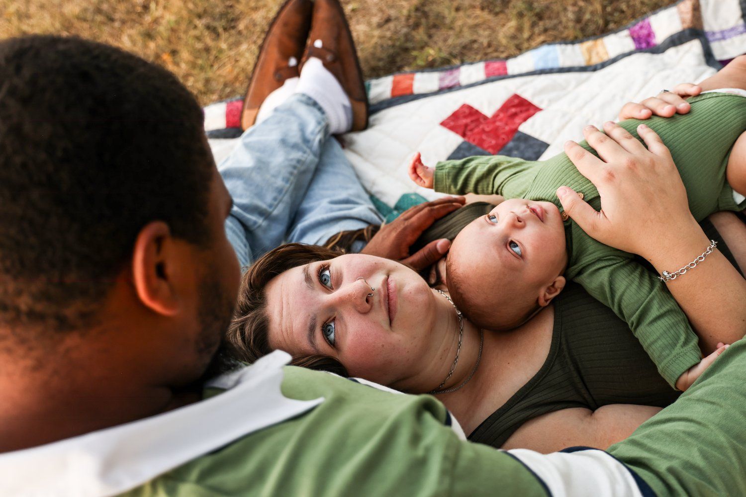 Family lying together on a blanket outdoors enjoying a tender moment in Abilene, Texas.