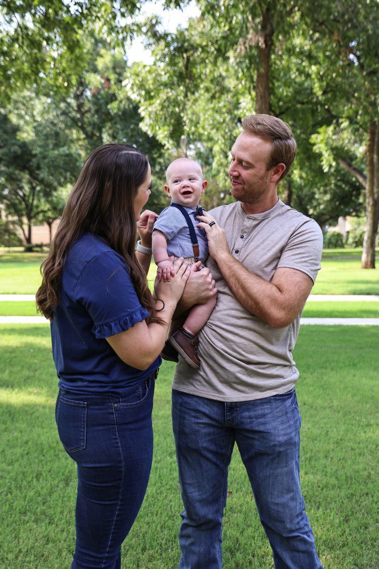 A family shares a joyful moment together on a grassy lawn during summer in Abilene, Texas.