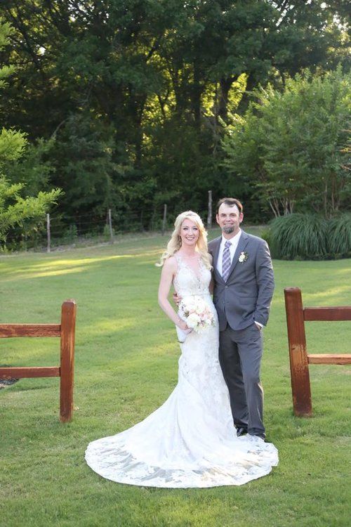 Wedding portrait in front of wooden fence with lush garden background.