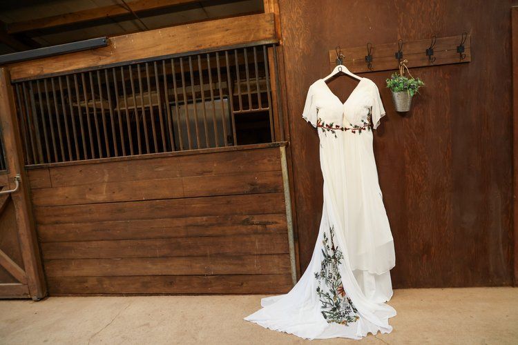 White wedding dress with floral embellishments displayed in a rustic barn setting in Abilene, Texas.