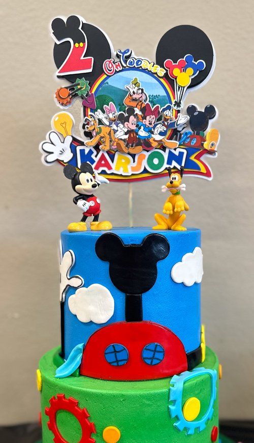 Colorful Mickey Mouse themed birthday cake with character toppers and decorative elements.