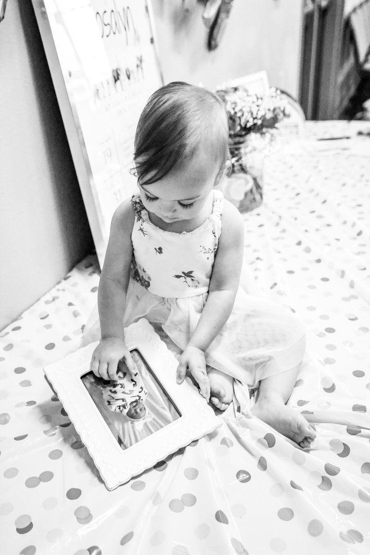Small child sitting on polka dot bedding while looking at a tablet device in Abilene, Texas.