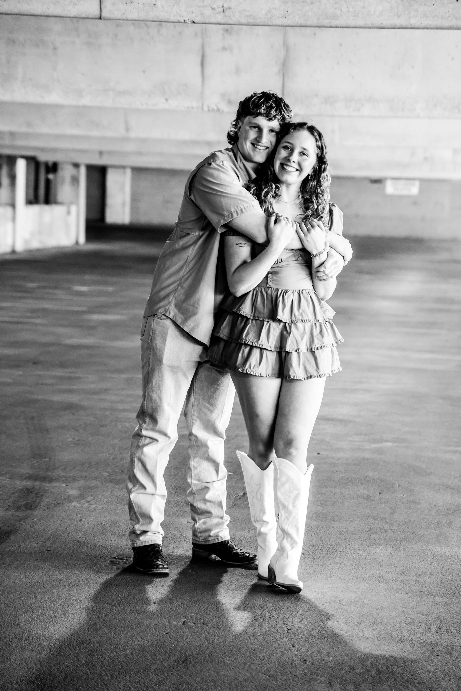 Black and white photo of couple in vintage-inspired outfits embracing in parking structure in Abilene, Texas.
