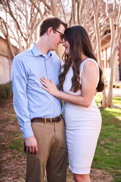 Romantic couple in casual attire sharing intimate moment among bare trees in Abilene, Texas.