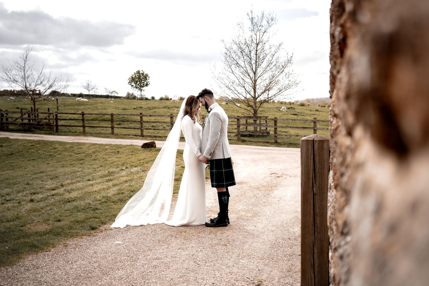 bride and groom at dodford manor, touching foreheads together on the pathway. groom wearing a kilt