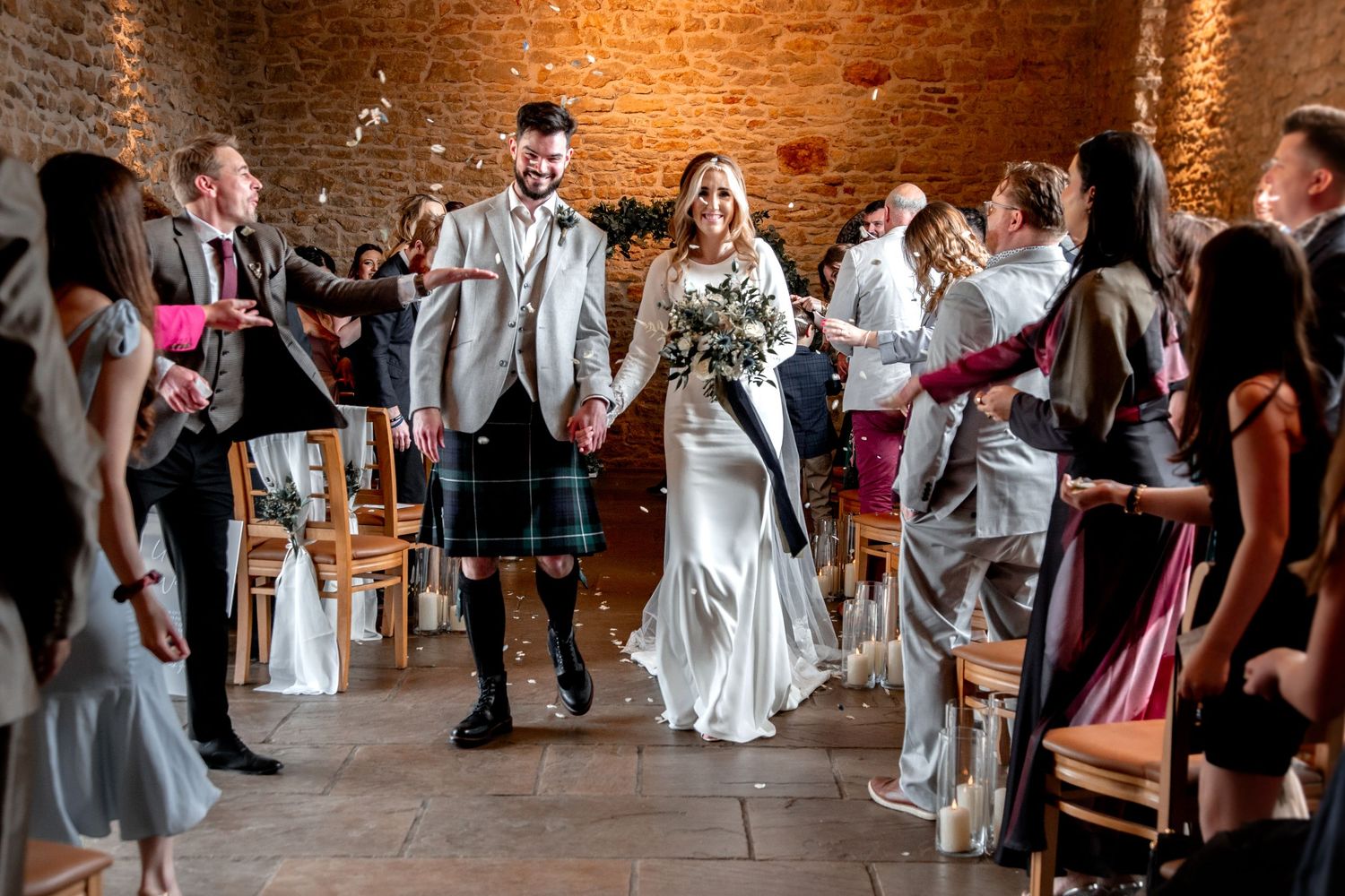 bride and groom at dodford manor after their ceremony, walking back up the aisle. guests throwing confetti over them. everyone smiling