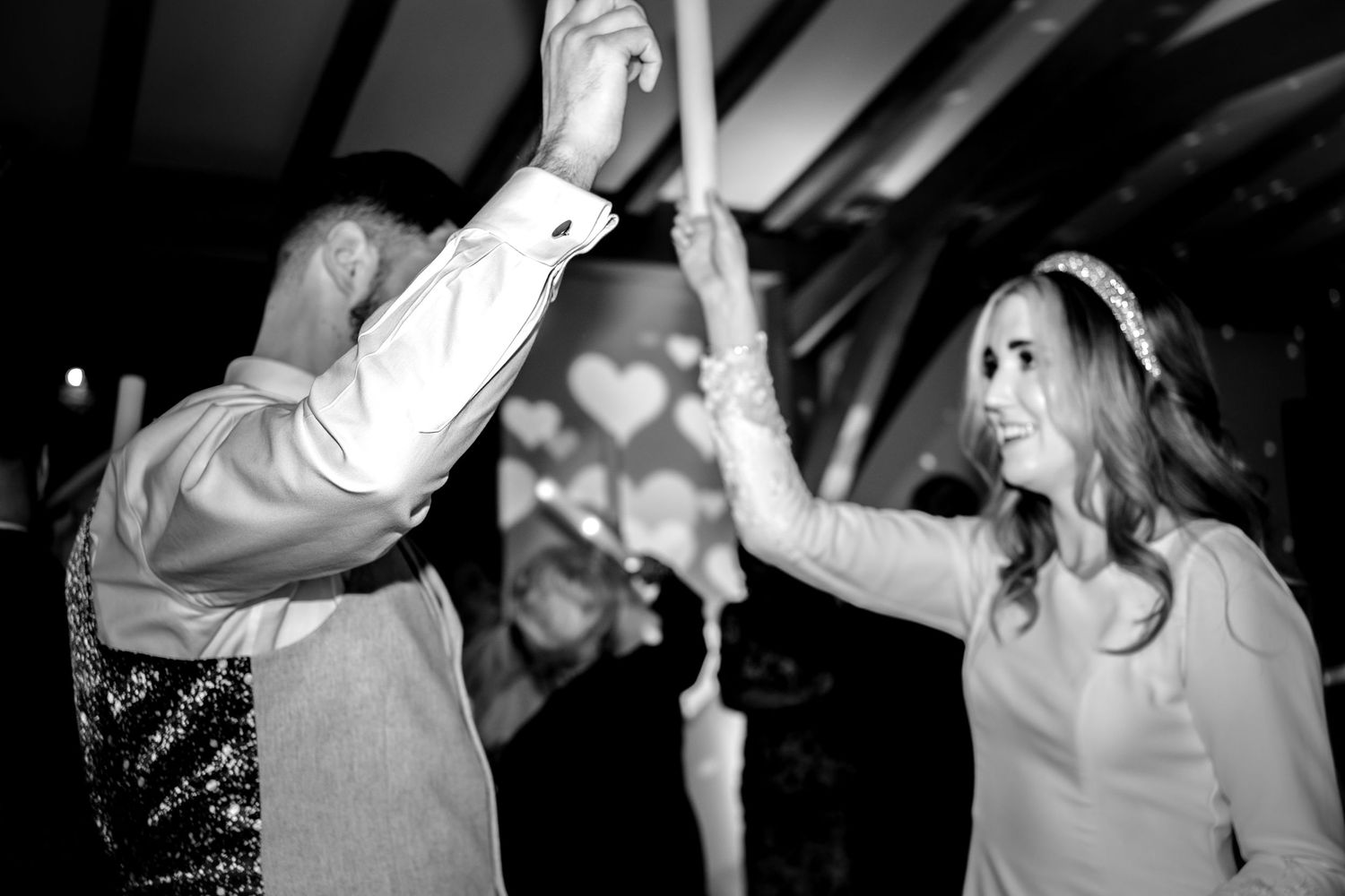 Bride and groom and dodford manor dancing and smiling, holding up glow sticks. Black and white image