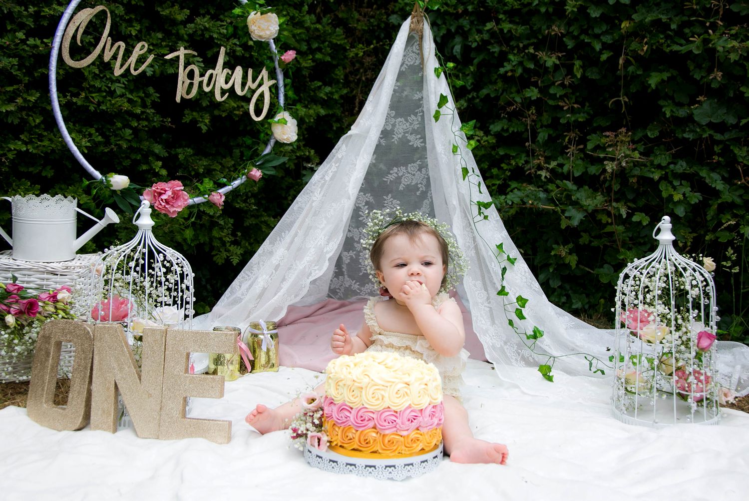 Outdoor cake smash photo shoot with little girl, Whimsical boho vibes with a flower crown. Girl eating the cake