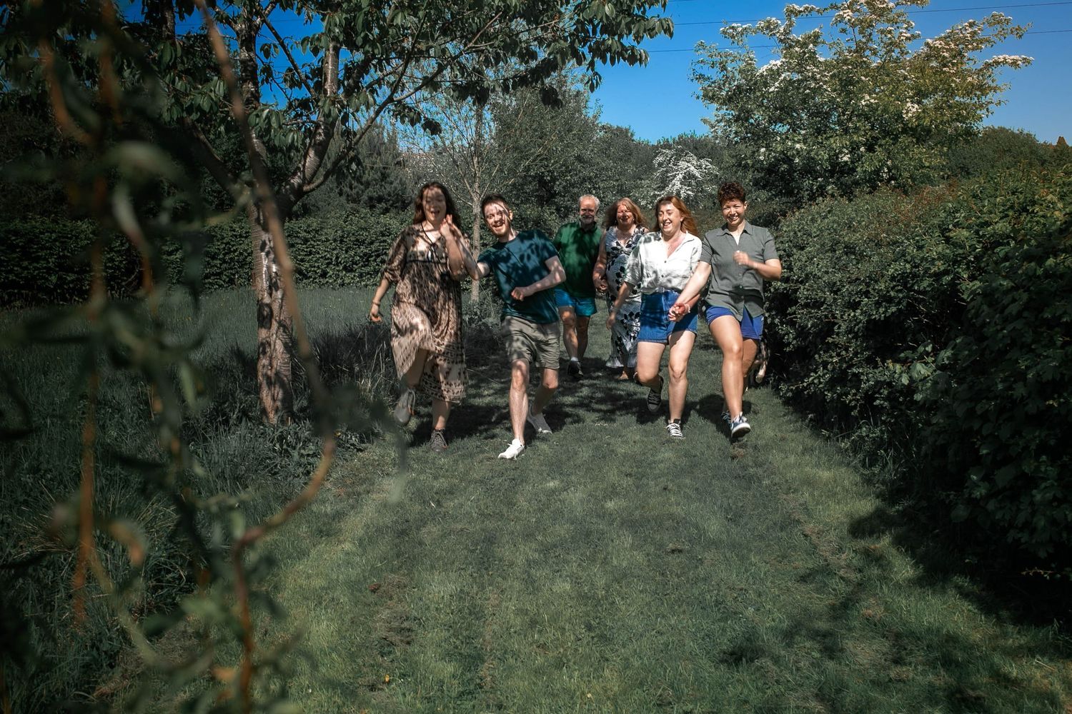 Family of six running toward the camera laughing and smiling