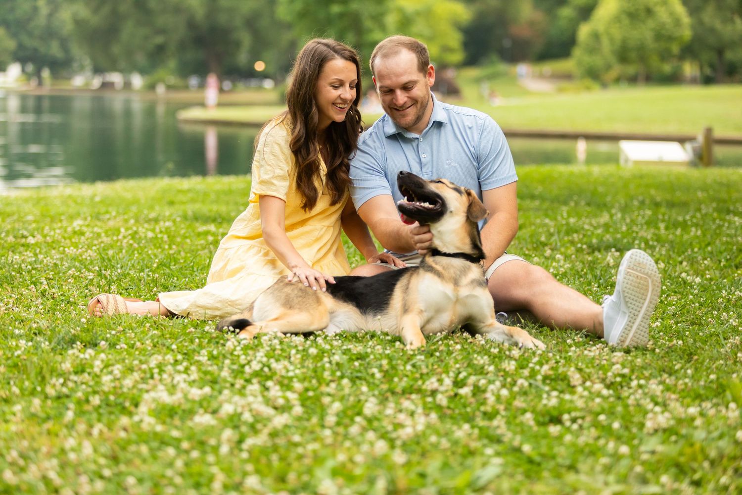 Happy couple relaxing on green grass lawn with flowers on sunny spring day in park setting.