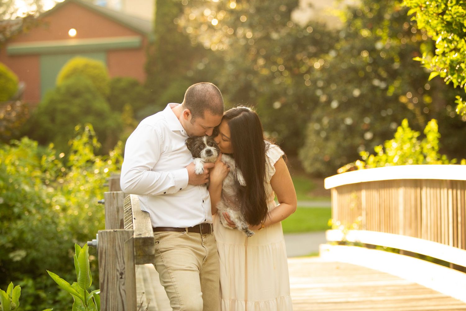 A romantic couple shares an intimate moment together on a wooden bridge during golden hour sunset.