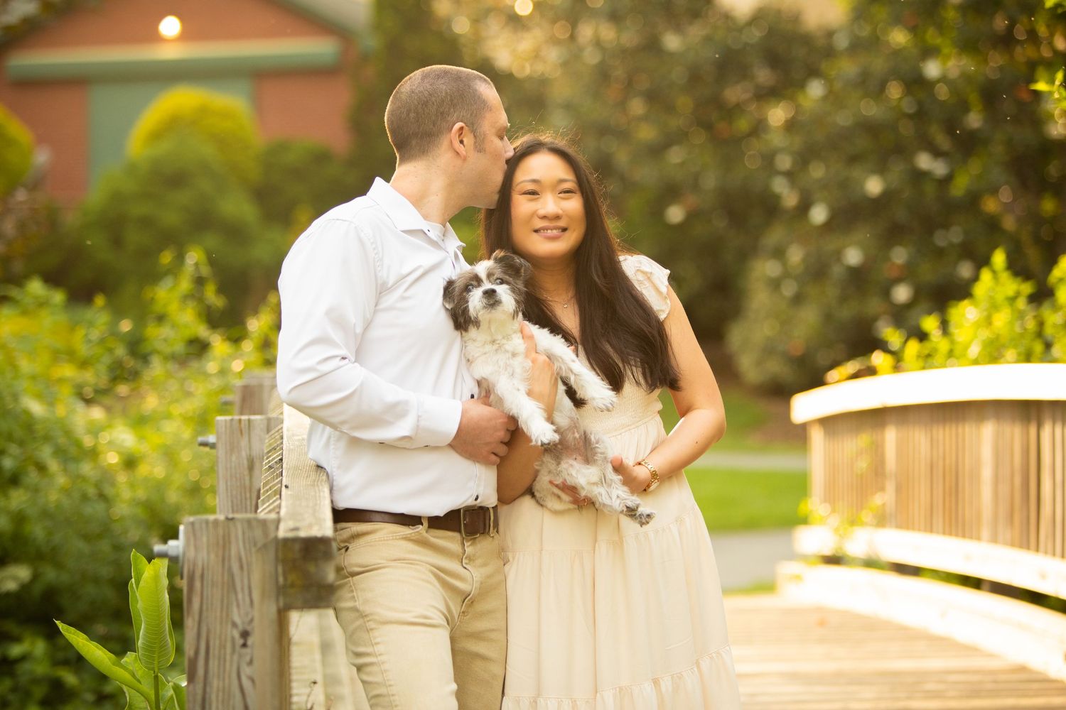 A lovable fluffy dog joins a couple on a romantic bridge in an outdoor garden setting during golden hour.