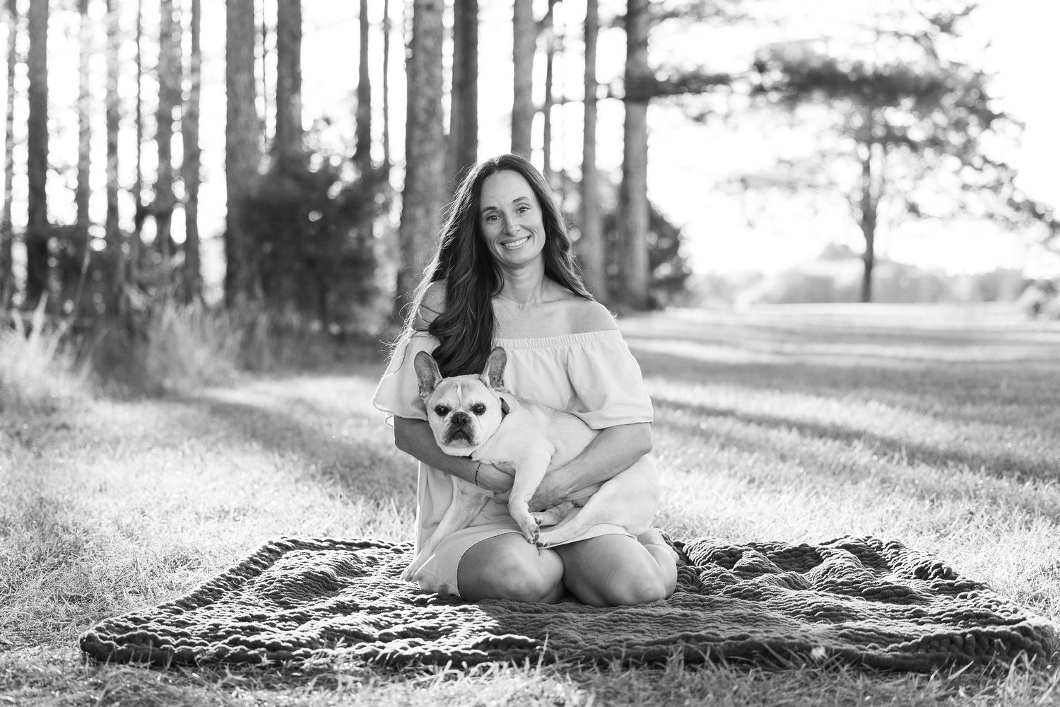 A black and white photo series of a person and corgi dog relaxing together on a blanket in a grassy outdoor setting.