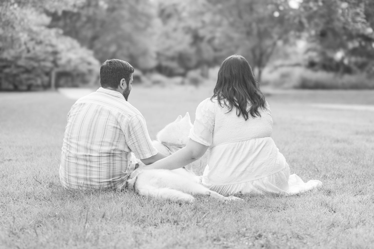 Couple relaxing together on grass while laying down in a park on a sunny summer day.