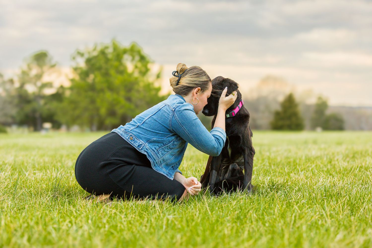 A couple lies together on lush green grass enjoying a peaceful moment in nature at sunset.