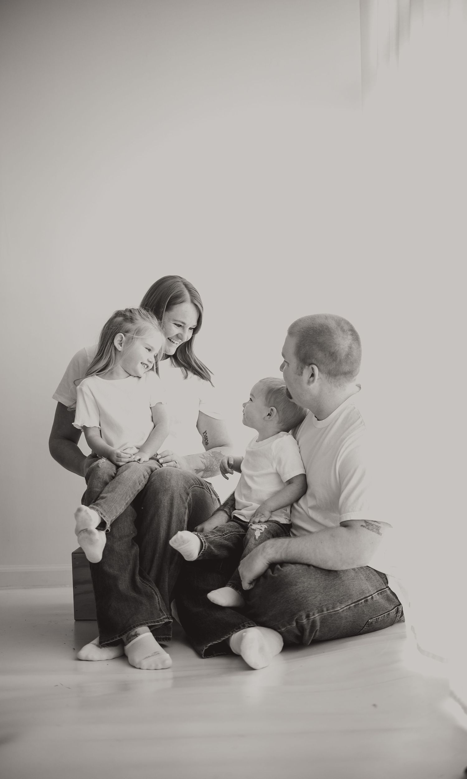 Family portrait captured against minimal white background in black and white.
